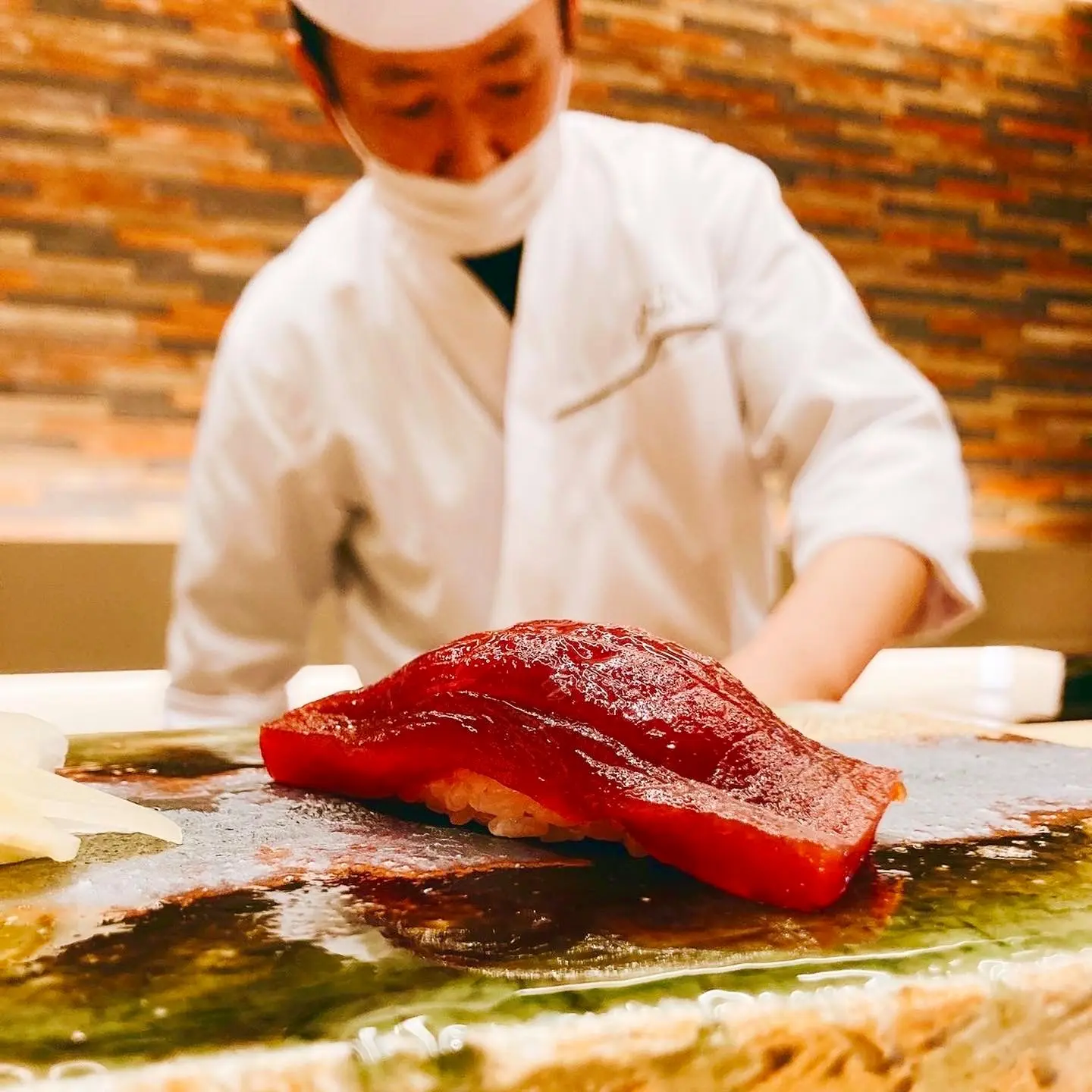 カウンターでマグロの柵に包丁を入れる大将